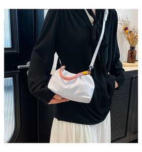 Detail of white pleated cloud bag with colorful braided handle and silver metal hardware