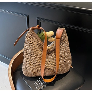 Detail of hollow straw weave texture and brown leather strap on a large hobo bag