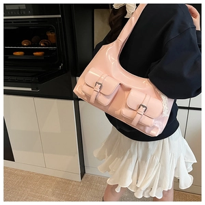Detail of pink patent leather shoulder bag featuring metal buckles and white lace trim