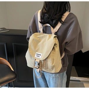 Detail of khaki drawstring backpack featuring branded flap with buckle and side zipper