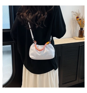 Detail of white pleated cloud bag with pink orange gradient woven handle and thin strap