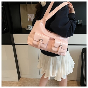 Side view of pink patent leather moon bag with buckle pockets on a model shoulder