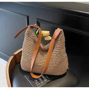 Detail of hand-woven straw bag with premium brown leather strap and textured finish
