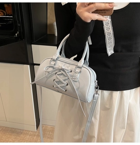 Dettaglio della borsa lucida celeste con un design a fiocco intrecciato stringato sul davanti