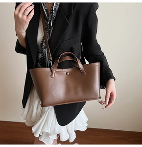 Detail of dark brown matte leather bucket bag shown with a minimalist metal ring strap