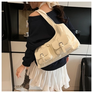 Detail of off-white large tote bag with glossy finish and double buckled front pockets