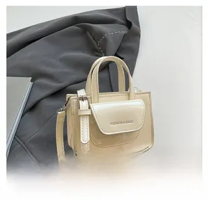 Detail der cremeweißen Mini-Quadrat Tasche aus Lackleder mit Fashion & Bags Aufschrift
