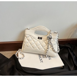 Close-up of beige quilted leather handbag with silver twist lock and chain strap