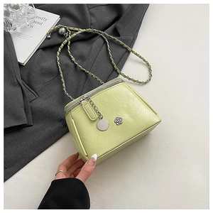Close-up of pistachio green chain bag featuring camellia metal detail and top zipper