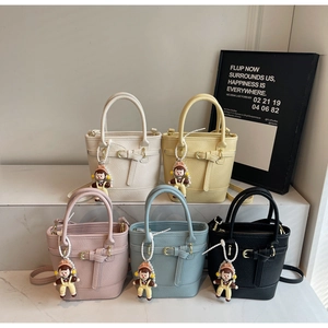 Detail view of colorful bucket bags with lychee texture and cute cartoon doll charms