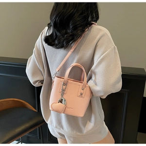 Pink bucket bag with lychee texture and heart charm, shown on model in a minimalist room