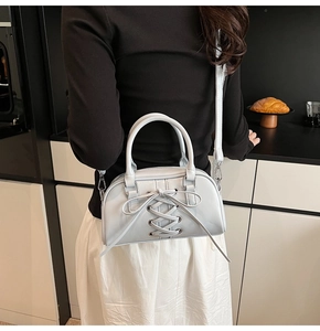 Modella che indossa una borsa a tracolla azzurra con fiocchi in una cucina moderna