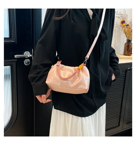 Detail view of pink pleated cloud bag with colorful woven handle on a female model