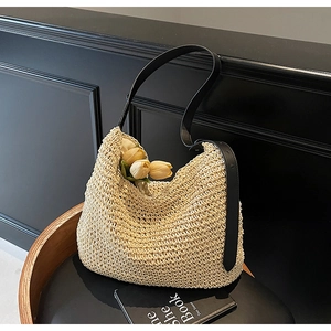 Close-up of woven shoulder bag texture with contrast black leather strap on a desk