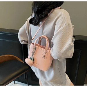 Detail of pink lychee leather bucket bag with silver chain heart pendant and top handles