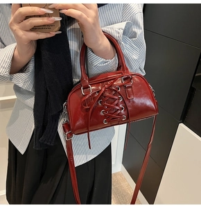Borsa a tracolla in pelle verniciata rosso scuro con lacci indossata per il tragitto quotidiano