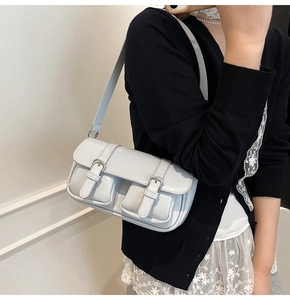Detail of light blue glossy underarm bag with silver buckles and patent leather texture