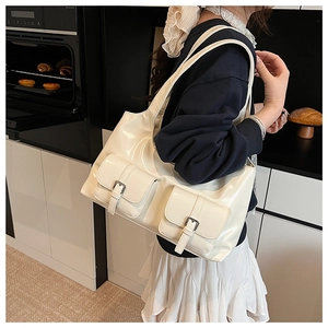Detail of cream shoulder bag featuring shiny finish and double front flap pockets