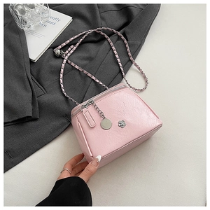 Detail of light pink textured leather mini bag with silver flower badge and chain strap