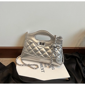Close-up of silver quilted crossbody bag with metal twist lock and chain strap detail