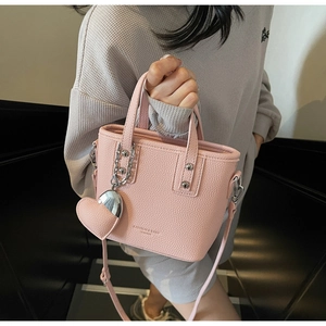 Detail of pink lychee texture bucket bag with silver heart charm and chain handle