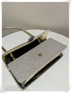 Detail of glittery silver diamond square clutch bag with golden mirror finish and strap