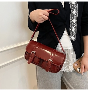Detail view of burgundy glossy patent leather underarm bag with double buckle flap design