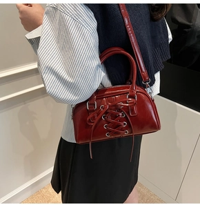 Dettaglio della borsa bauletto retrò bordeaux con lacci intrecciati e ganci argentati