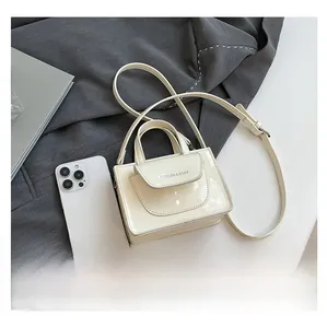 Kleine cremefarbene Lackledertasche neben Smartphone zur Darstellung der kompakten Größe