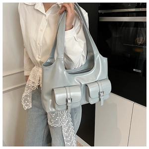 Close-up of a light blue glossy PU leather tote bag with stylish buckle pockets
