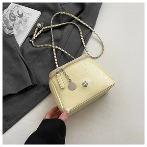 Detail of creamy yellow chain crossbody bag with camellia pin on grey blazer