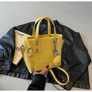 Detail of yellow lychee grain leather bucket bag with silver chain and heart charm