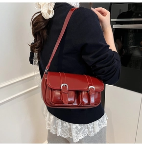 Detail shot of a vintage burgundy shoulder bag with silver buckles on a female model