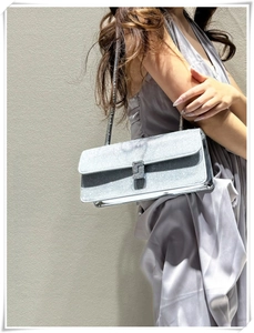 Detail of silver sequin shoulder bag with rhinestone buckle on gray satin dress