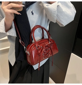 Dettaglio ravvicinato di borsa in pelle cerata rosso scuro con lacci incrociati