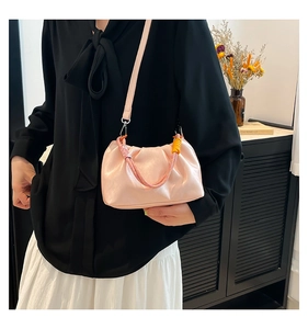 Close-up of pink pleated cloud bag with braided handle and slender shoulder strap