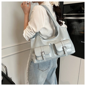 Detail of light blue patent leather tote bag with functional front pockets and glossy finish