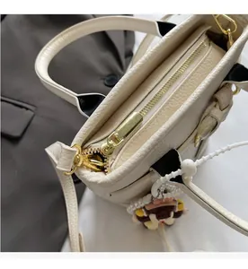 Detail of smooth gold zipper and pebble leather texture on an off-white bucket bag