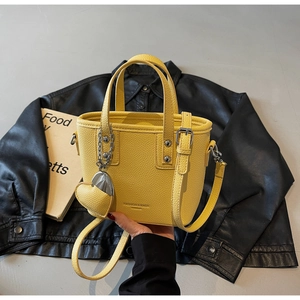 Detail of yellow lychee pattern bucket bag with heart charm and metallic lettering