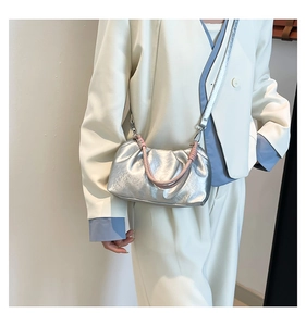 Silver metallic pleated crossbody bag shown with pink woven handle on a white suit model