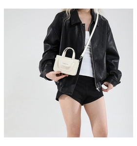 Detail einer minimalistischen creme-weißen PU-Leder Umhängetasche mit modischem Schriftzug