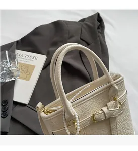 Detail of cream lychee texture handbag featuring premium gold hardware and sturdy dual handles
