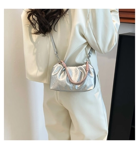 Detail of silver pleated cloud bag with pink braided handle on a model in minimalist interior