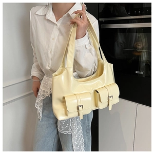 Detailed view of cream yellow tote bag featuring dual front pockets with metal buckle strap