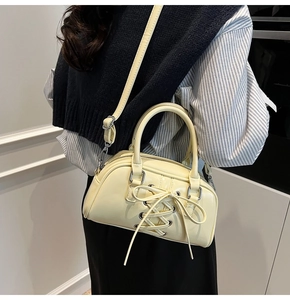Dettaglio borsa a tracolla giallo crema con design stringato e tracolla regolabile
