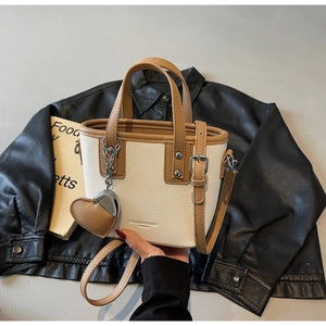 Close-up of cream bucket bag with lychee texture, brown edges and heart pendant