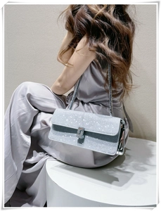 Detail of silver rhinestone baguette bag with metallic chain on elegant grey satin dress