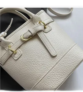 Detail of creamy white bucket bag featuring premium pebble grain leather and gold hardware
