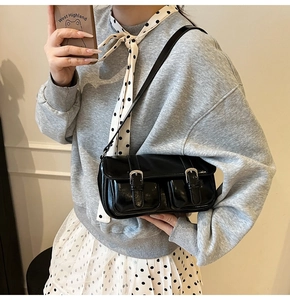 Detail of black patent leather shoulder bag with glossy finish and double pockets