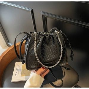 Close-up of black woven leather bucket bag with silver chain strap and drawstring closure